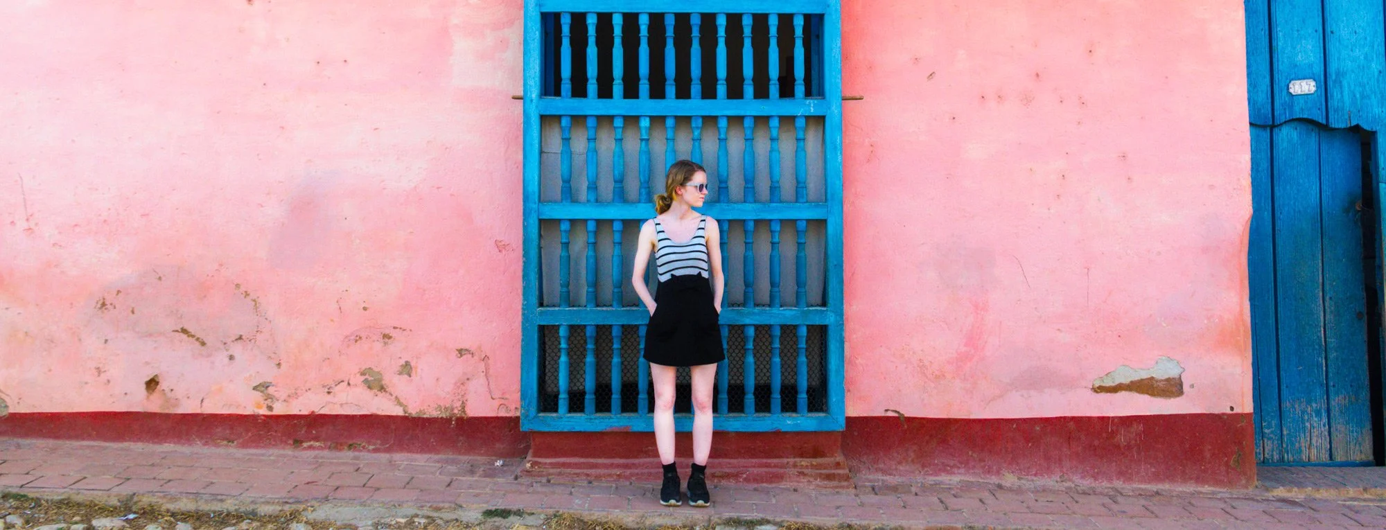 Vibeke standing in front of a pink wall and a blue window